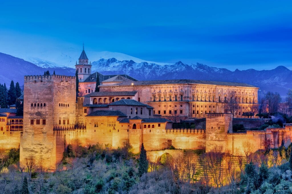 Night view of the Alhambra illuminated with Sierra Nevada snowy mountains in the background