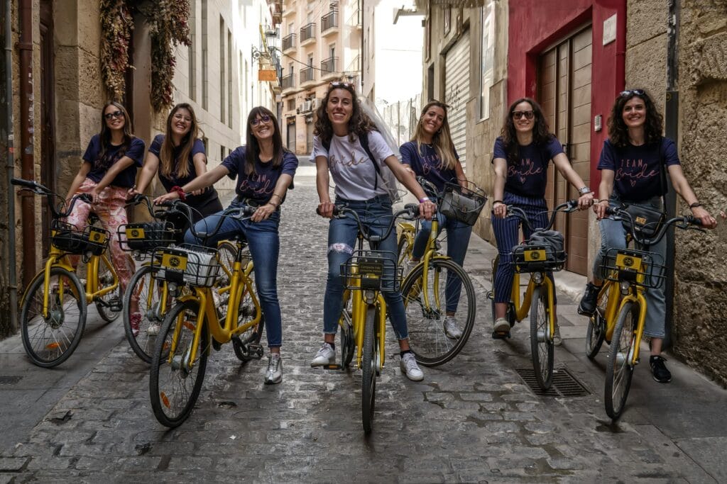 Group of young international students riding bicycles along a sunny street in Alicante