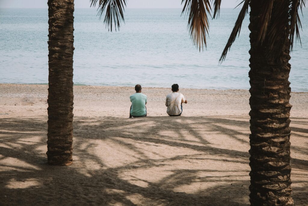 Two international students relaxing on a sunny beach in Málaga, combining Spanish learning with a Mediterranean lifestyle