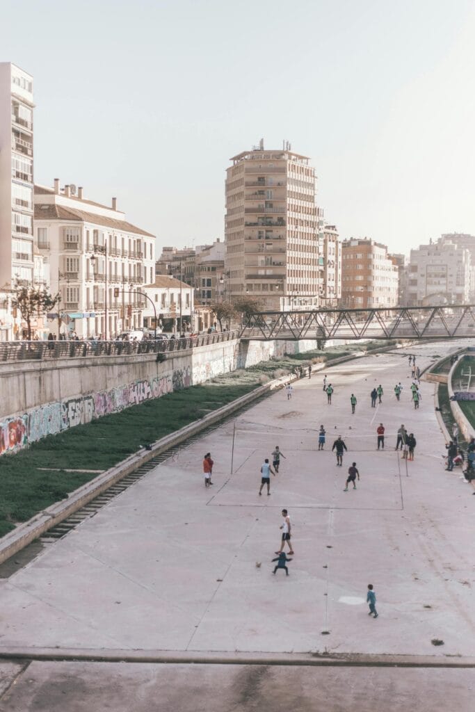 People playing and relaxing along the riverside promenade in Málaga on a sunny day