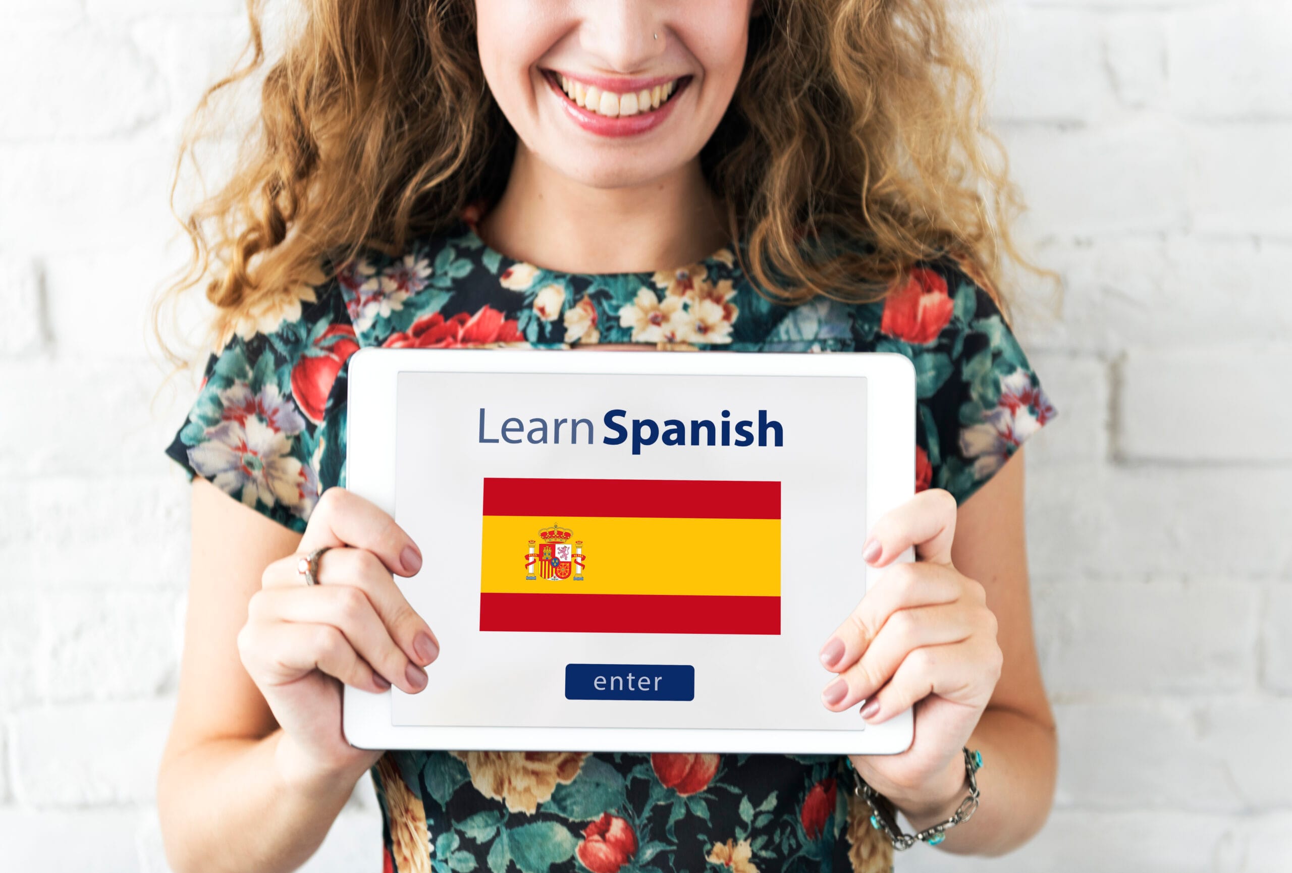 Student holding a "Learn Spanish" sign outdoors, representing international Spanish learners.